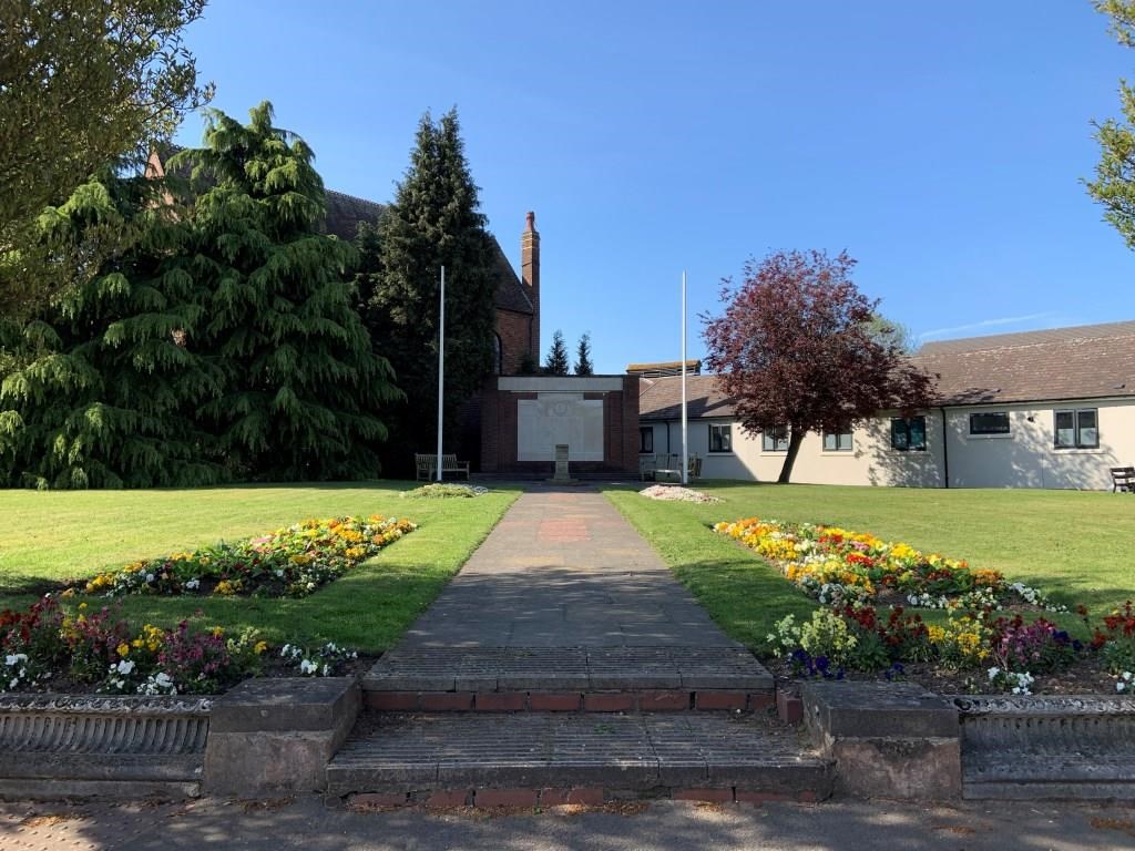 stone war memorial in landscaped gardens